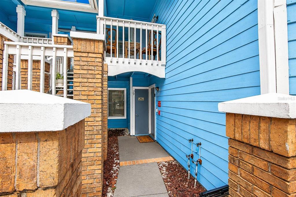 A blue-sided building exterior features a brick pillar, a walkway, and a second-story balcony — 2739 N POINCIANA BOULEVARD UNIT 79, KISSIMMEE, FL