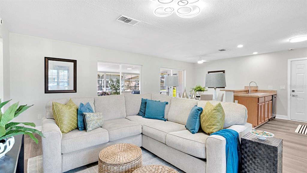 A living room features a large sectional sofa, two wicker ottomans, and an open kitchen — 10230 GENESEE LANE, ORLANDO, FL