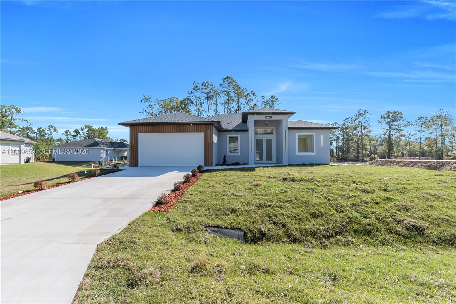 A modern single-story house features a two-car garage, a gray exterior, and a paved driveway — 1220 Euclid Ave, Lehigh Acres FL 33972, LEHIGH ACRES, FL