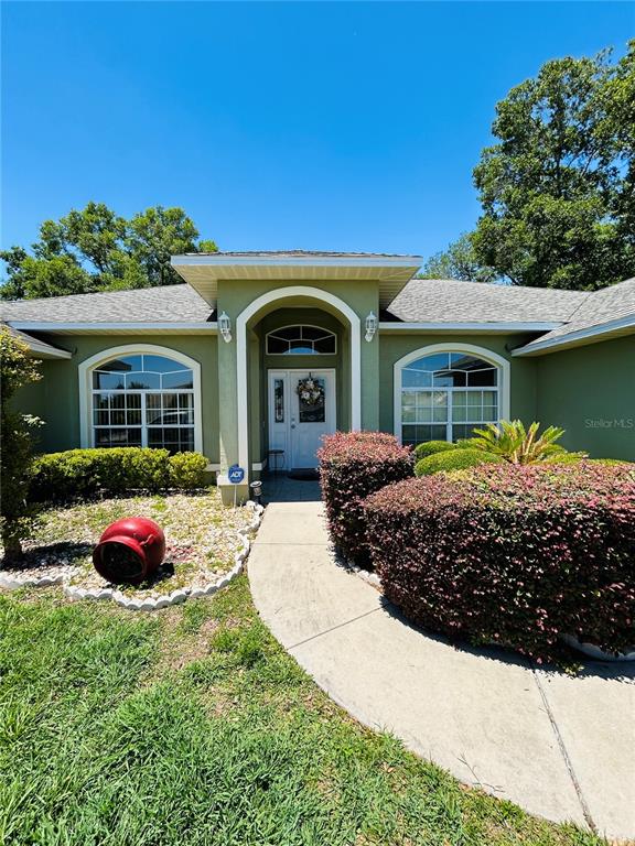 The exterior of a light green house features a covered entryway and a concrete walkway — 13620 SW 48TH COURT, OCALA, FL