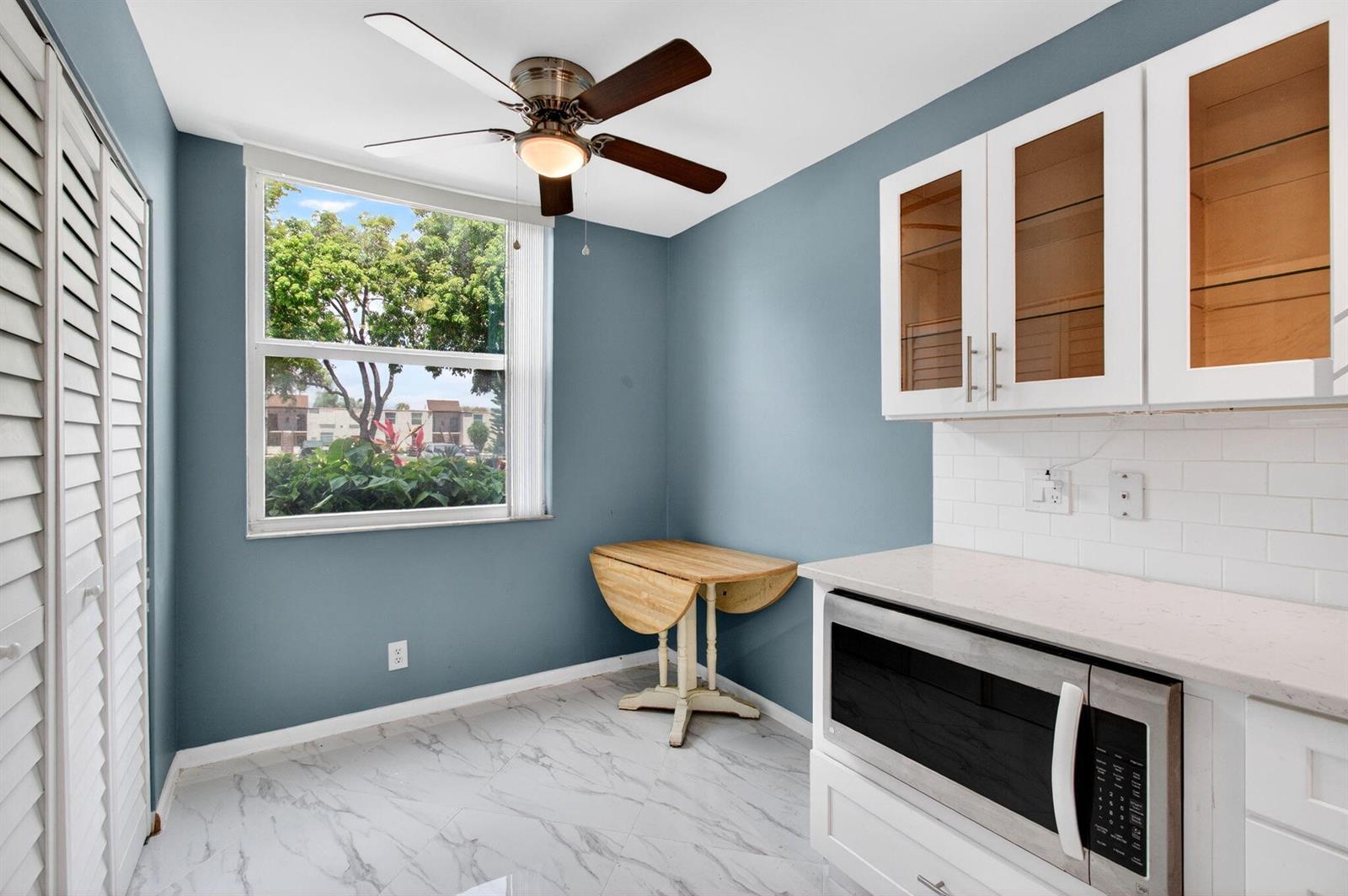 A kitchen area features blue walls, white cabinets, a ceiling fan, and a drop-leaf table — 18 Willowbrook Lane # 103, Delray Beach FL 33446, DELRAY BEACH, FL