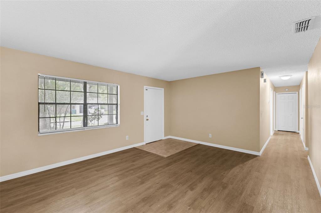 An empty living room with light-colored walls, wood-look flooring, and a white front door — 113 LIDO ROAD, WINTER SPRINGS, FL