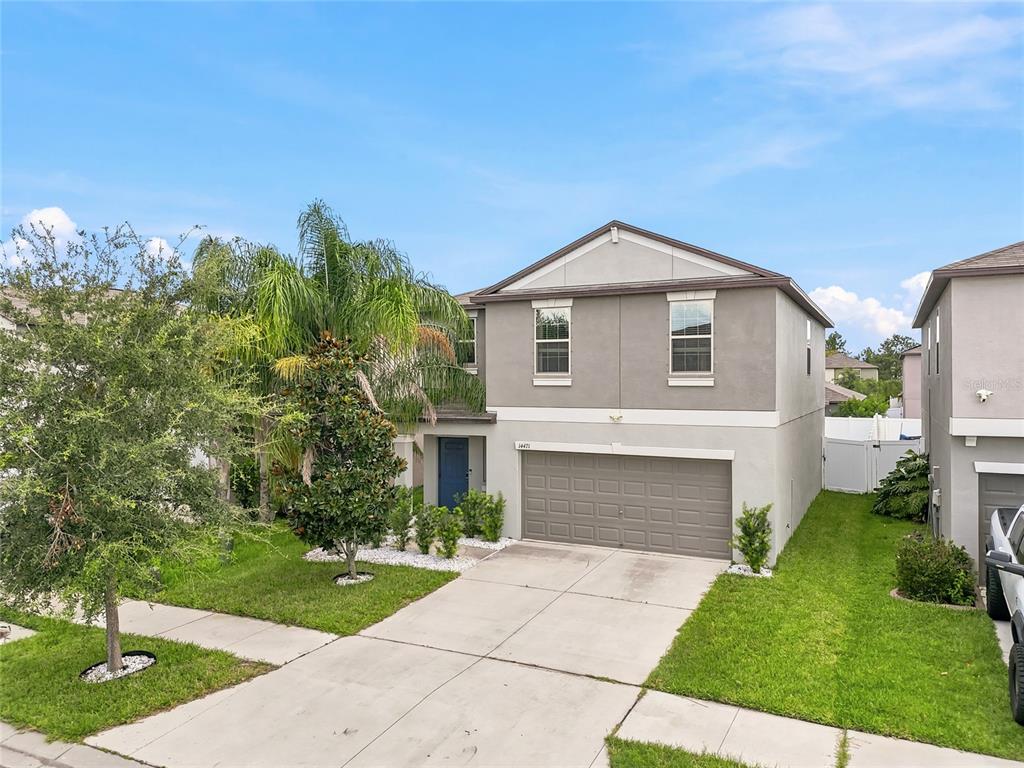 A two-story suburban house features a gray stucco exterior, a two-car garage, and a palm tree — 14471 ENGLISH LAVENDER DRIVE, WIMAUMA, FL
