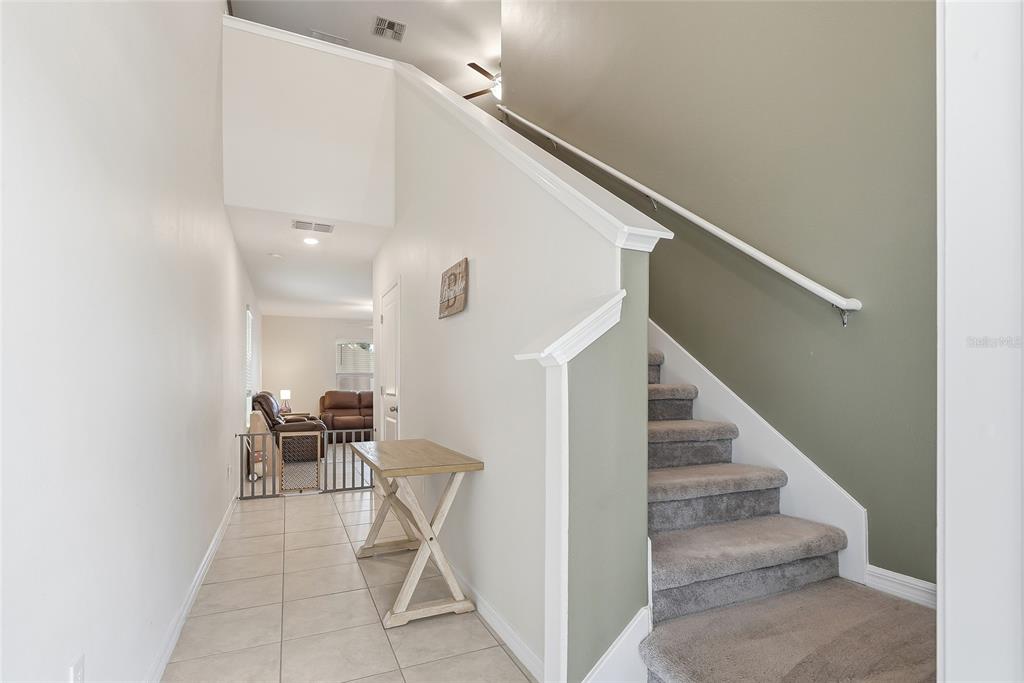 A tiled entryway features a wooden console table and a carpeted staircase with a handrail — 14471 ENGLISH LAVENDER DRIVE, WIMAUMA, FL