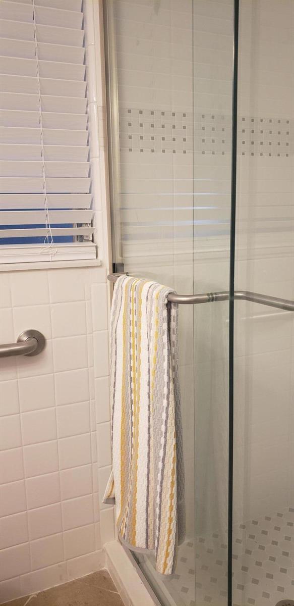 A tiled shower stall with a glass door and a striped towel hanging on the handle — 4107 SE Barcelona Street, Stuart FL 34997, STUART, FL