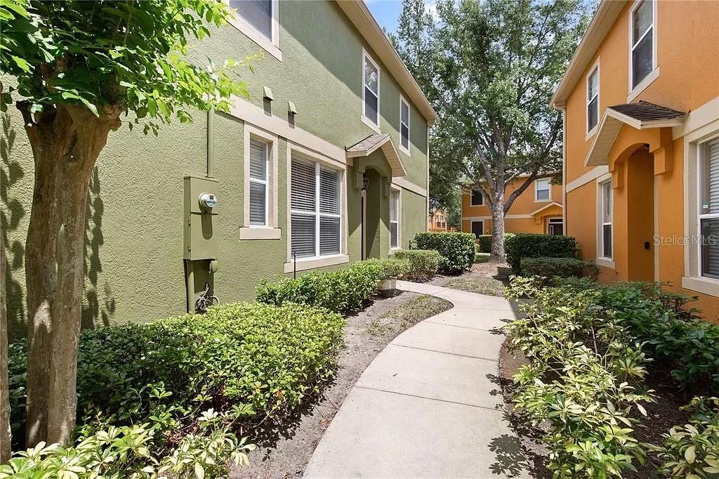 A concrete walkway leads between a green building and an orange building with landscaping — 1131 LITTLE GEM LOOP, SANFORD, FL