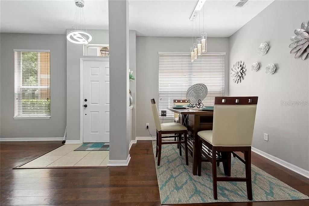A dining area features a wooden table, chairs, a patterned rug, and a front door — 1131 LITTLE GEM LOOP, SANFORD, FL