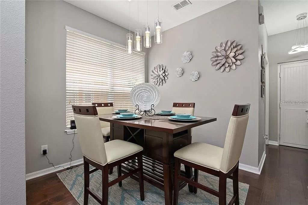 A dining area features a dark wood table with four chairs under modern pendant lights — 1131 LITTLE GEM LOOP, SANFORD, FL