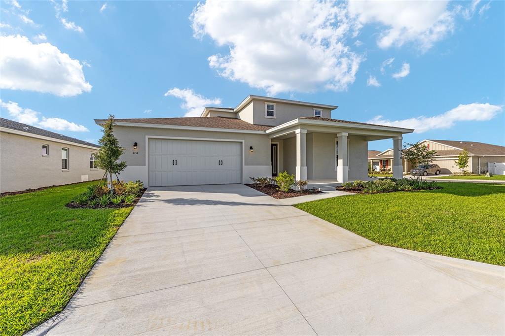 A two-story suburban house with a gray exterior, a two-car garage, and a covered porch — 7157 SW 57TH PLACE, OCALA, FL