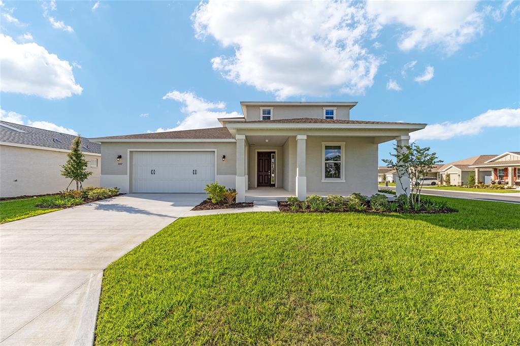 A single-story suburban house with a two-car garage, covered entryway, and a manicured lawn — 7157 SW 57TH PLACE, OCALA, FL