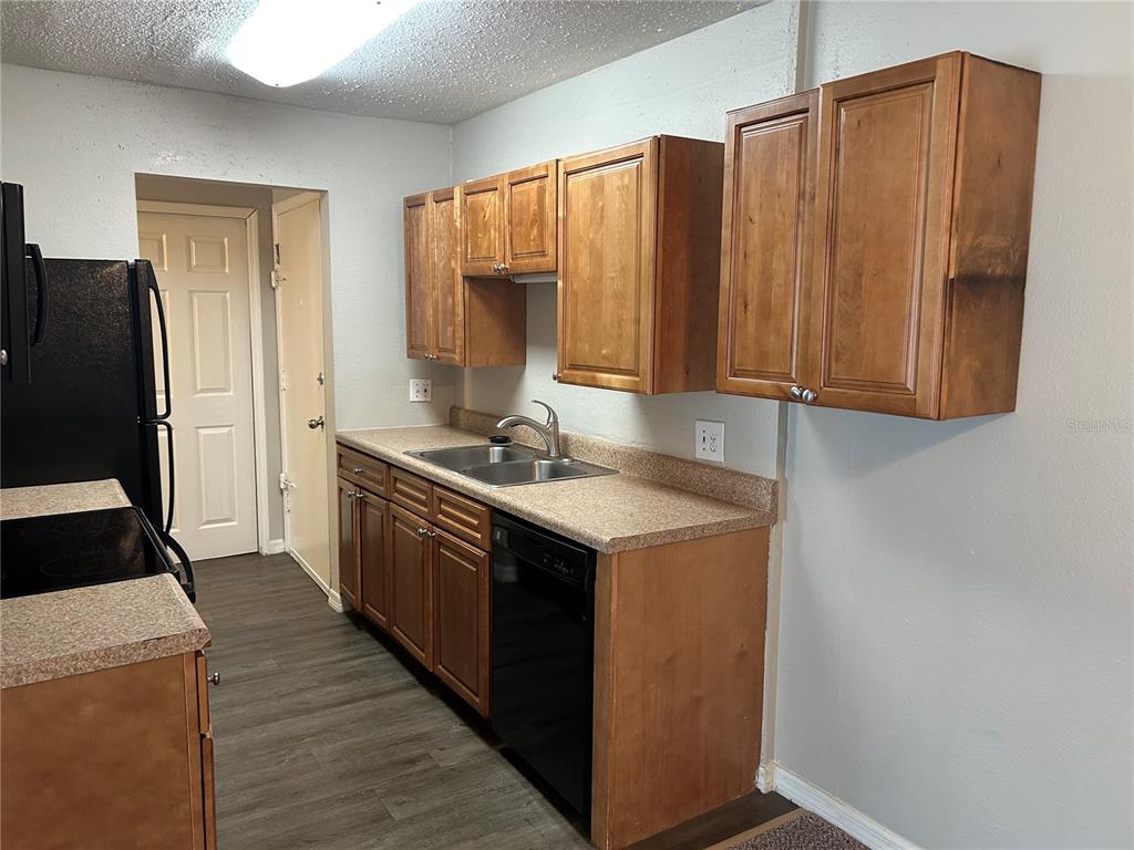 A kitchen features wood cabinets, a laminate countertop, a double sink, and black appliances — 1695 LEE ROAD UNIT A103, WINTER PARK, FL