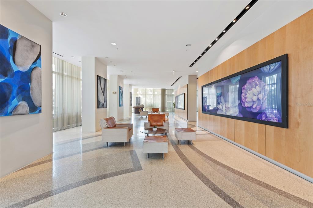 A modern lobby features a terrazzo floor, wood-paneled walls, and several seating areas with artwork — 150 E ROBINSON STREET UNIT 1415, ORLANDO, FL