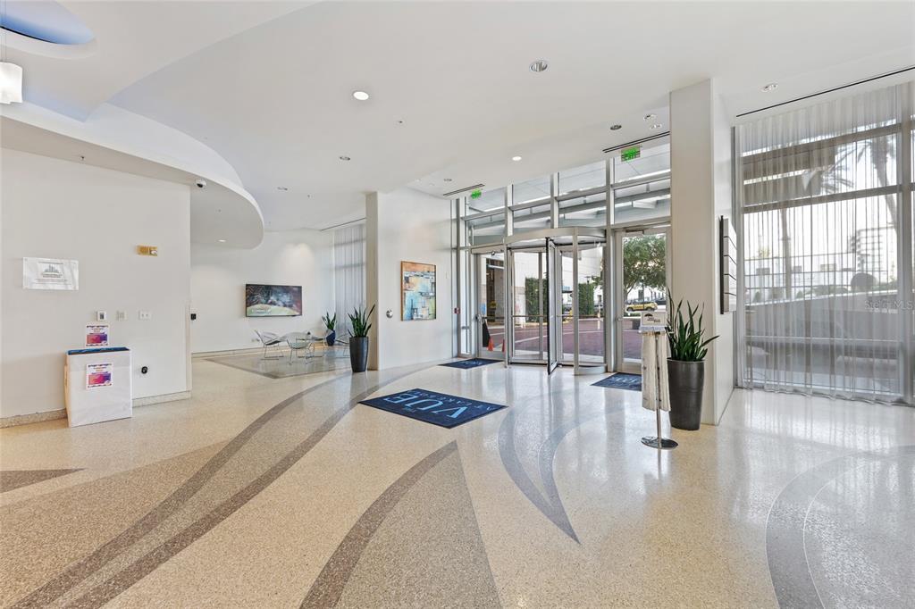 A modern building lobby features a revolving glass door, terrazzo flooring, and potted plants — 150 E ROBINSON STREET UNIT 1415, ORLANDO, FL