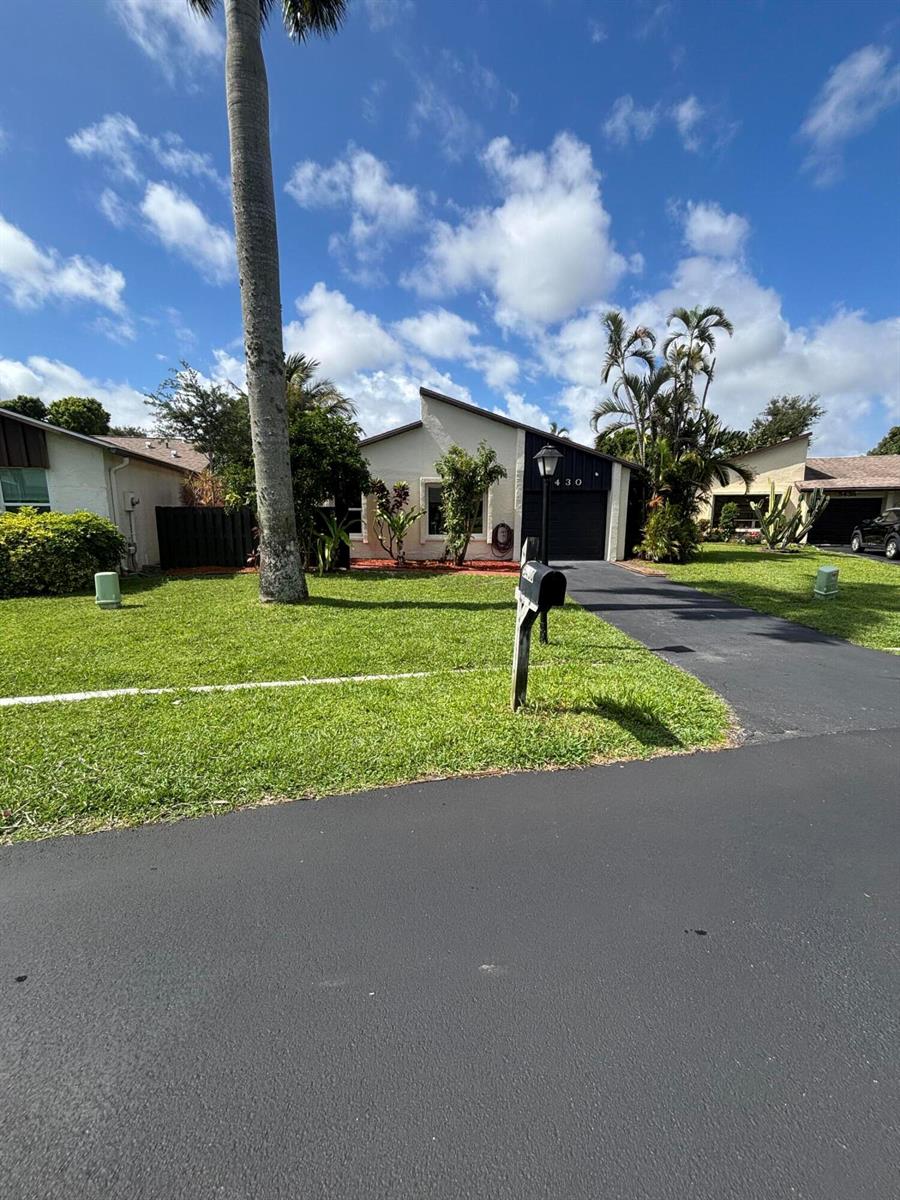 A brick walkway leads along the side of a house with red mulch and plants — 5430 Mirror Lakes Boulevard, Boynton Beach FL 33472, BOYNTON BEACH, FL