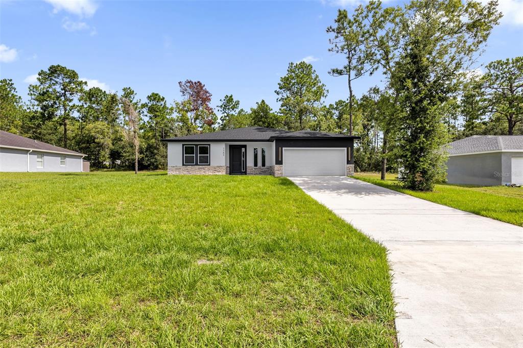 A single-story house with a white exterior, stone accents, and a two-car garage — 7753 SW 131 ST LANE, OCALA, FL