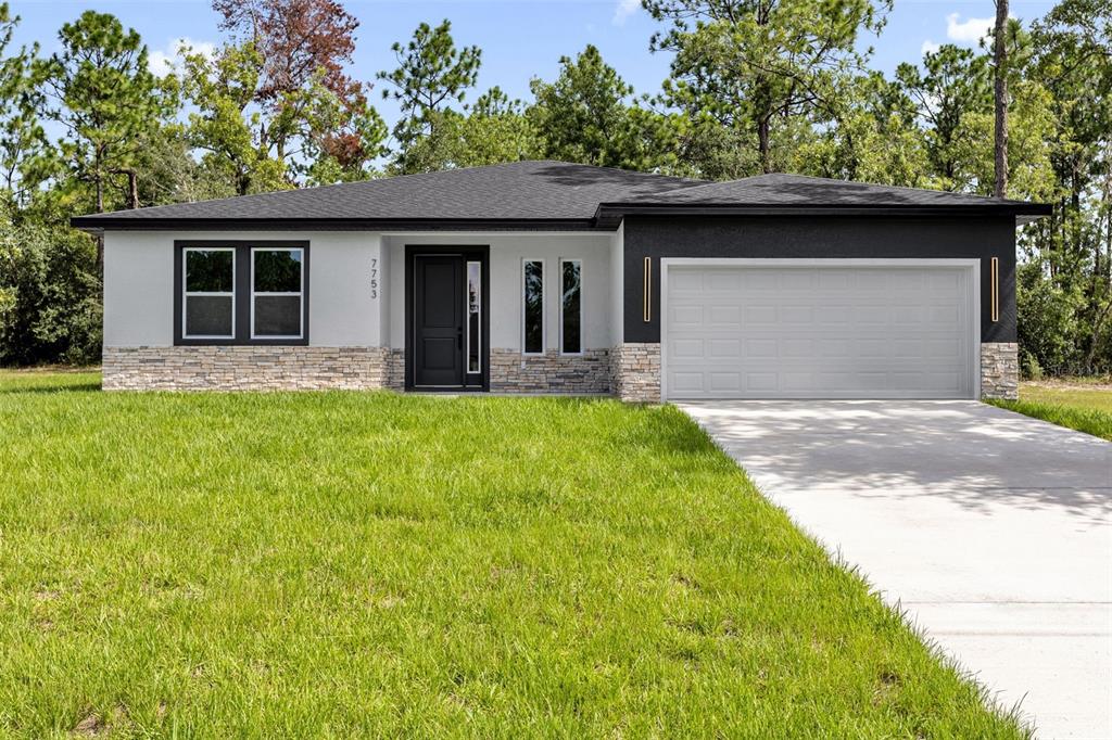 A single-story house with a white and black exterior, stone accents, and a two-car garage — 7753 SW 131 ST LANE, OCALA, FL
