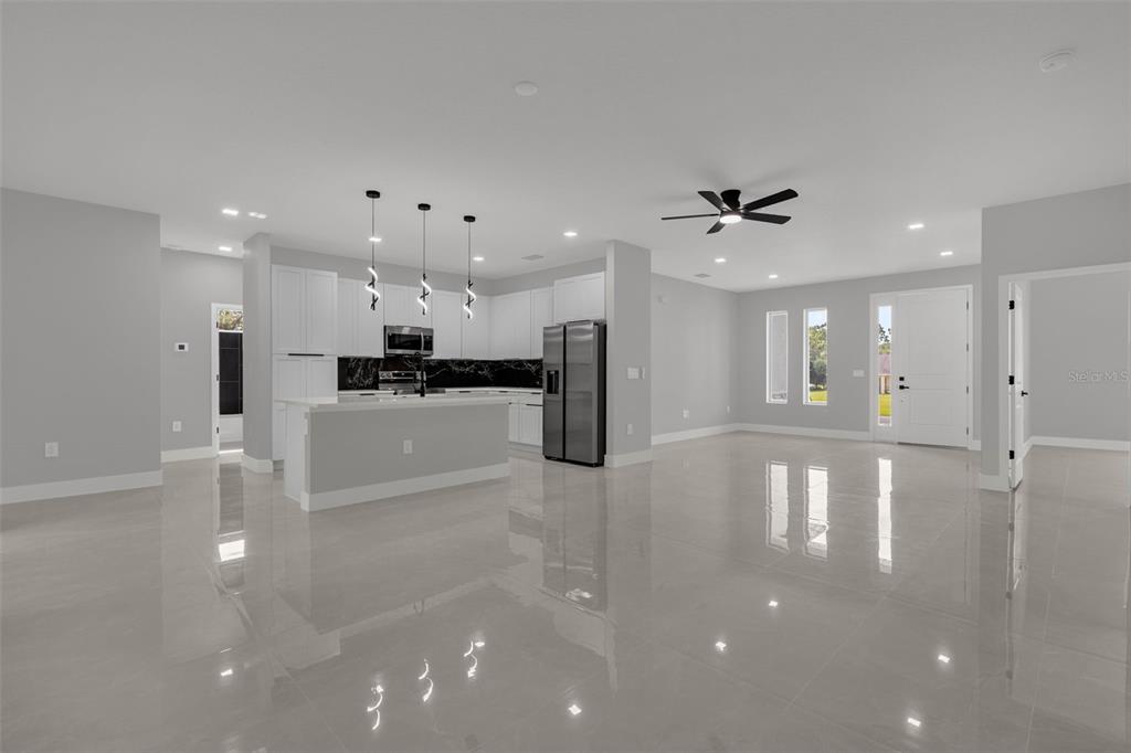 An open-concept kitchen and living area featuring white cabinets, stainless steel appliances, and tile flooring — 7753 SW 131 ST LANE, OCALA, FL