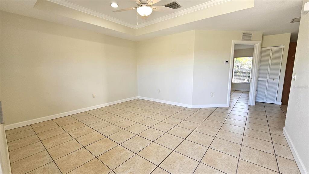 An empty room with beige tile flooring, a tray ceiling, and a doorway leading outside — 309 BOUNDARY BOULEVARD UNIT B, ROTONDA WEST, FL