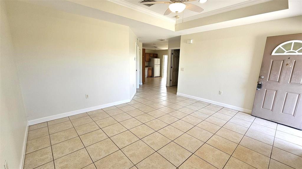 A tiled living room features a ceiling fan and an entryway leading to a kitchen — 309 BOUNDARY BOULEVARD UNIT B, ROTONDA WEST, FL