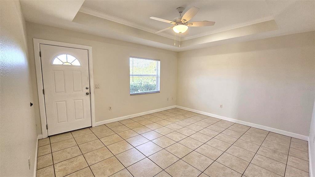 An empty room features light-colored tile flooring, a ceiling fan, and a white entry door — 309 BOUNDARY BOULEVARD UNIT B, ROTONDA WEST, FL