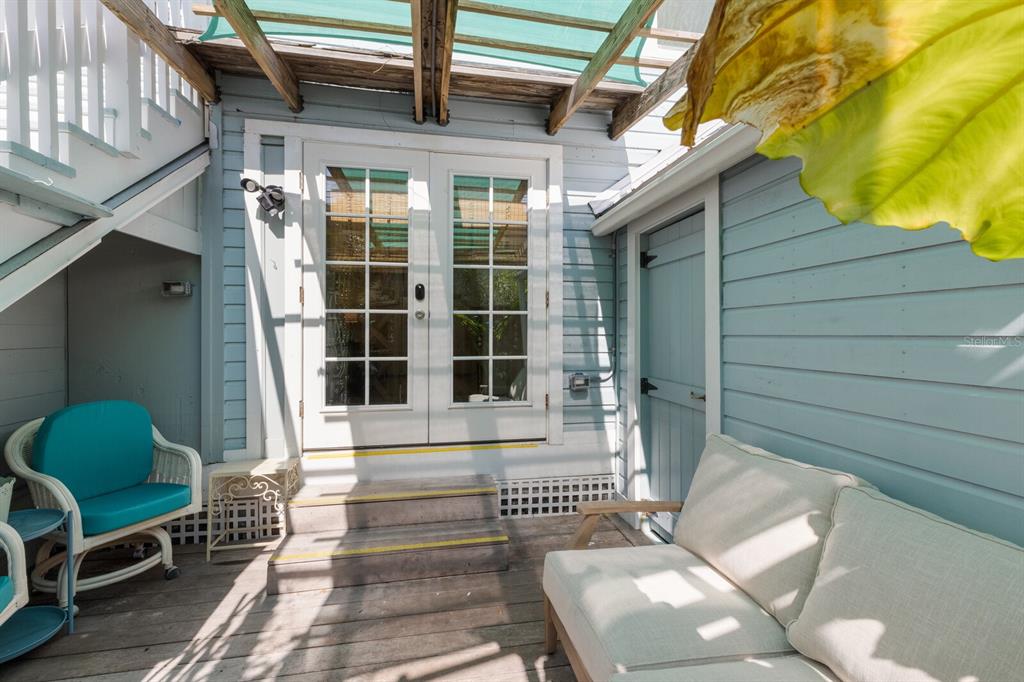 A wooden deck features a white couch, a wicker chair, and double glass doors — 370 E RAILROAD AVENUE UNIT 1, BOCA GRANDE, FL