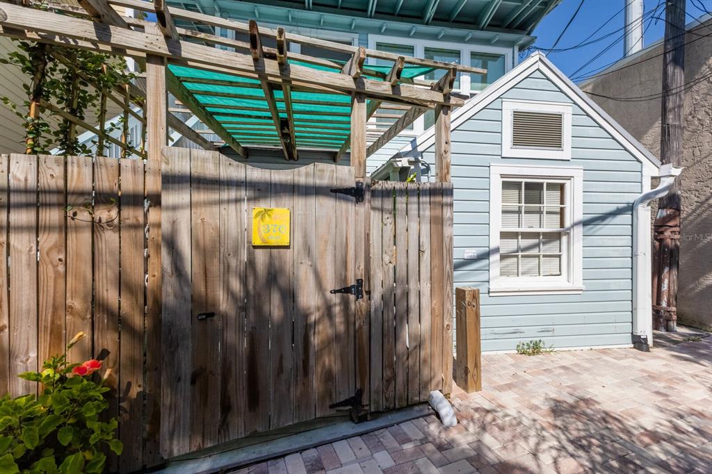 A wooden gate with a yellow sign stands next to a light blue house exterior — 370 E RAILROAD AVENUE UNIT 1, BOCA GRANDE, FL