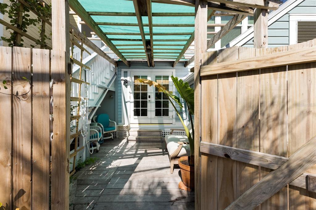 A wooden deck with a pergola, outdoor seating, and a staircase leading to a house entrance — 370 E RAILROAD AVENUE UNIT 1, BOCA GRANDE, FL