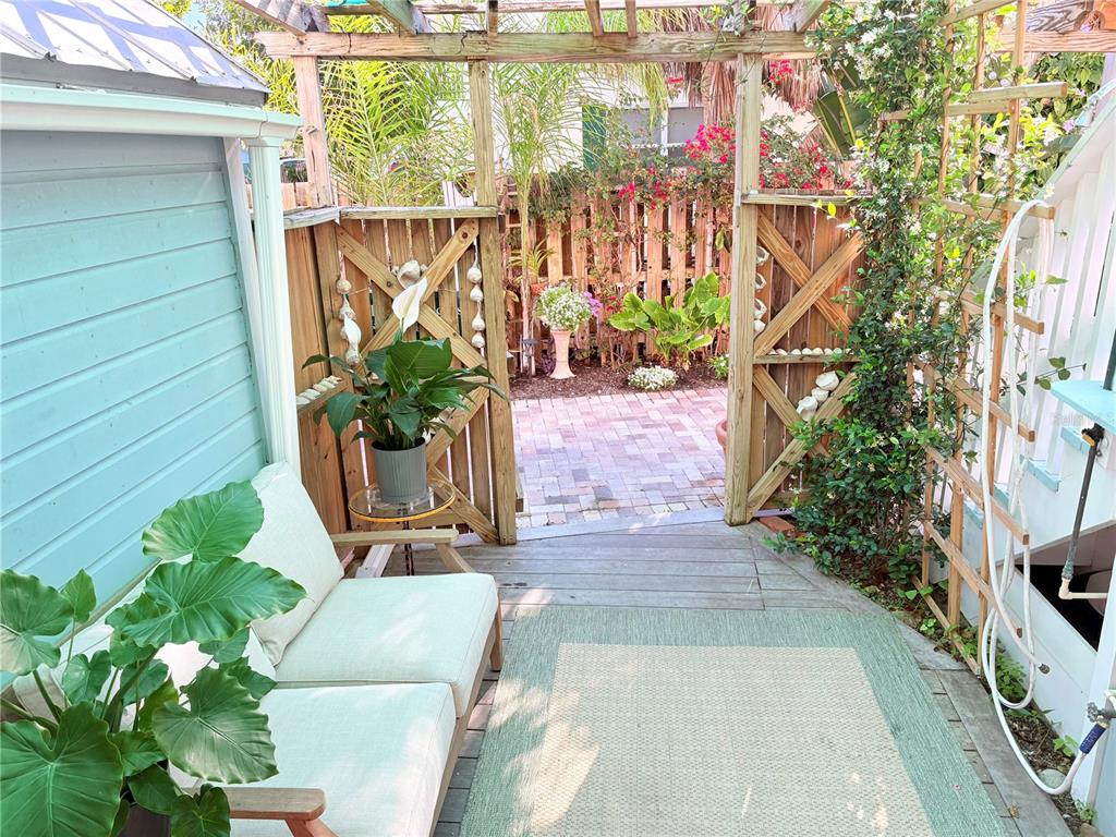 A wooden deck with a sofa and pergola leads to a brick patio and garden — 370 E RAILROAD AVENUE UNIT 1, BOCA GRANDE, FL