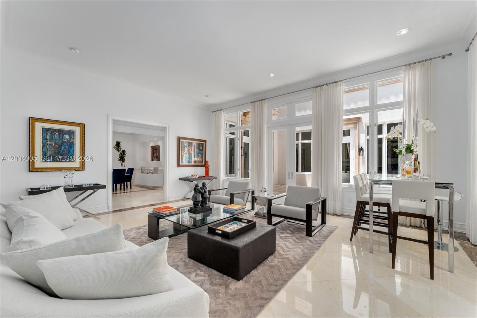 A bright living room features white furniture, a glass coffee table, and large floor-to-ceiling windows — 255 Cocoplum Rd, Coral Gables FL 33143, CORAL GABLES, FL