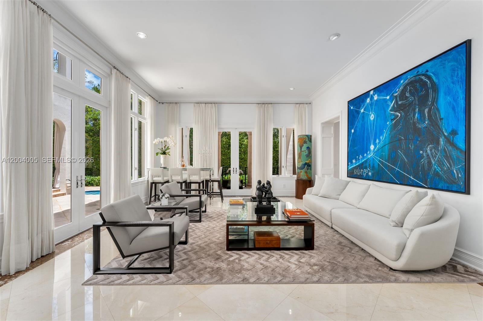 A bright living room features a white sofa, two armchairs, a glass coffee table, and art — 255 Cocoplum Rd, Coral Gables FL 33143, CORAL GABLES, FL