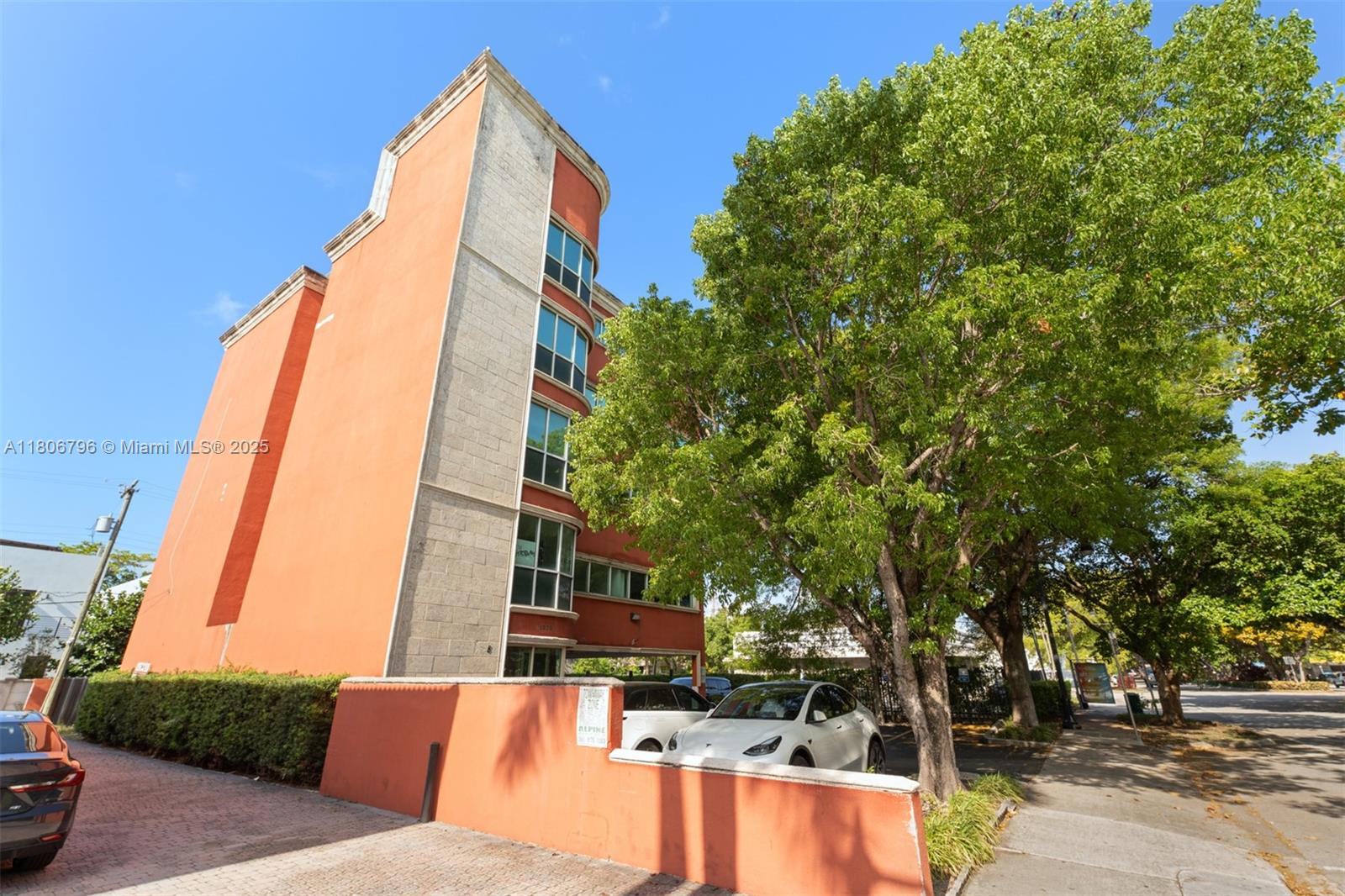 A multi-story orange building with a parking area and large trees stands under a sky — 1378 Coral Way # 3, Miami FL 33145, MIAMI, FL