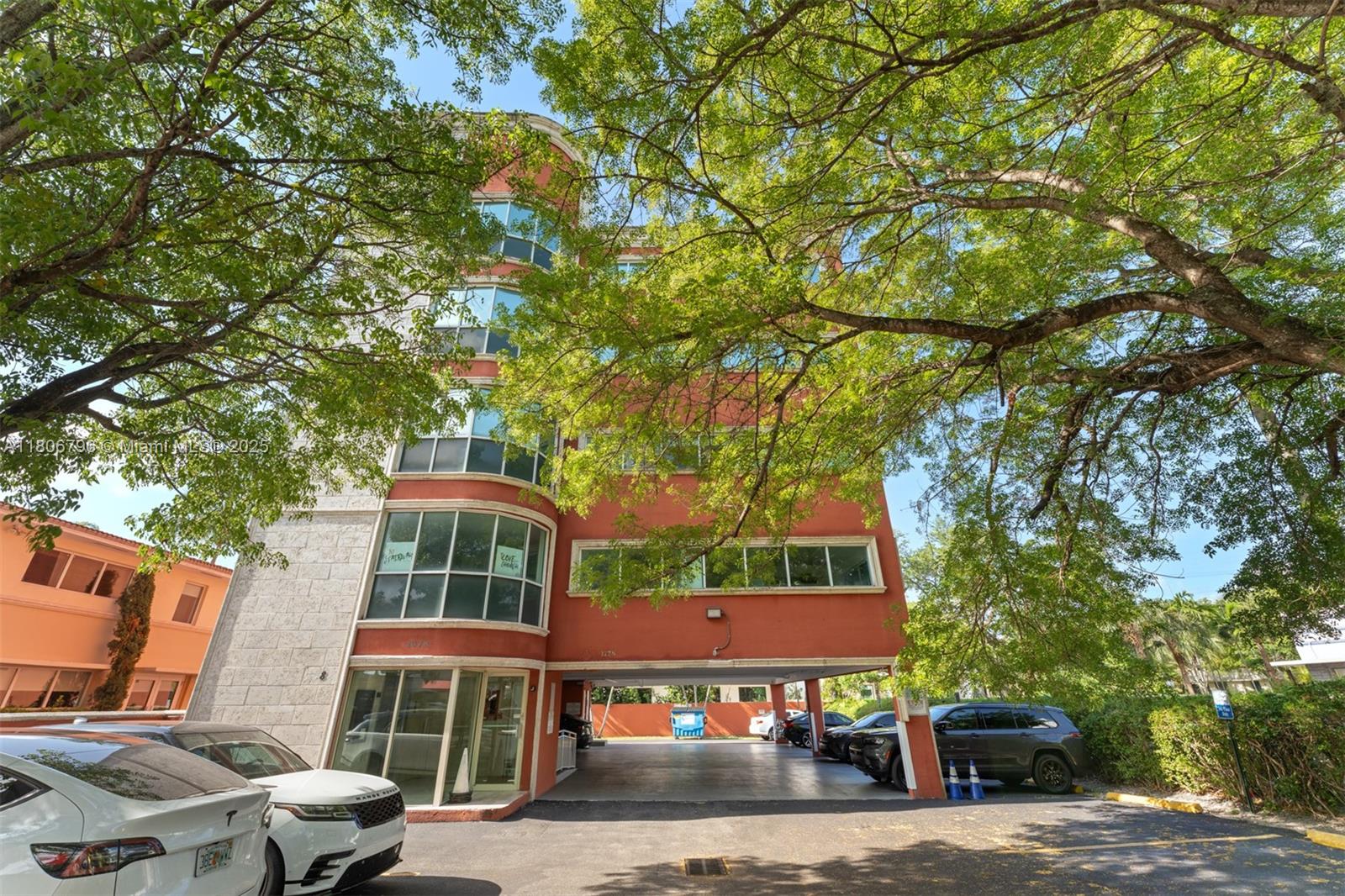A multi-story red building with a ground-level parking area and large trees in front — 1378 Coral Way # 3, Miami FL 33145, MIAMI, FL