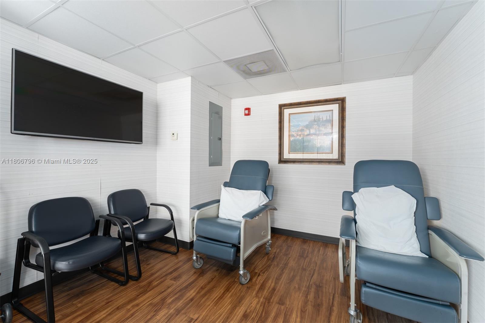 This waiting room features wood-look flooring, white paneled walls, a television, and four chairs — 1378 Coral Way # 3, Miami FL 33145, MIAMI, FL