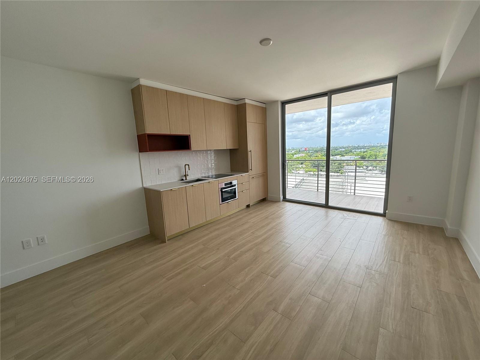 A modern kitchen with light wood cabinets and a balcony overlooking a city landscape — 90 NE 32 # 1016, Miami FL 33137, MIAMI, FL