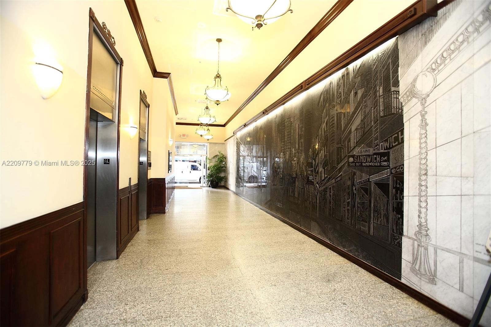 A long building lobby features a large black-and-white mural, elevators, and hanging pendant lights — 28 W FLAGLER ST, Miami FL 33130, MIAMI, FL