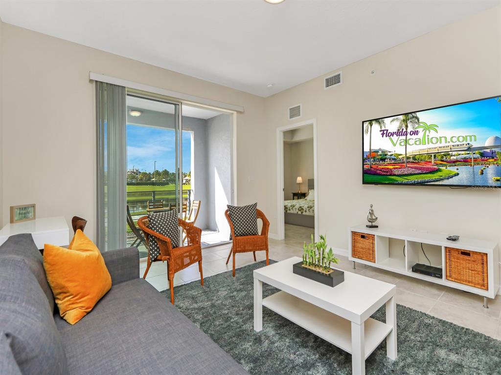 A living room features a gray sofa, two wicker chairs, a white coffee table, and television — 3151 PARADOX CIRCLE UNIT 104, KISSIMMEE, FL