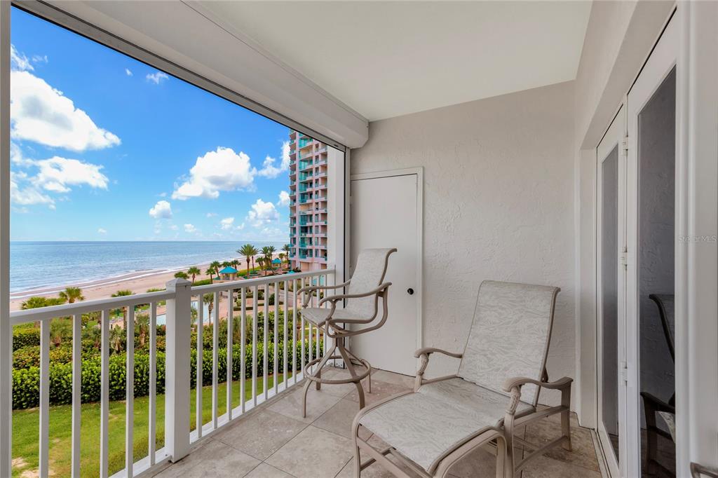 A balcony with tile flooring, two chairs, and a view of the ocean and beach — 1582 GULF BOULEVARD UNIT 1506, CLEARWATER BEACH, FL