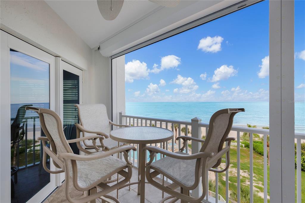 A balcony with a table and chairs overlooks the ocean under a blue sky — 1582 GULF BOULEVARD UNIT 1506, CLEARWATER BEACH, FL