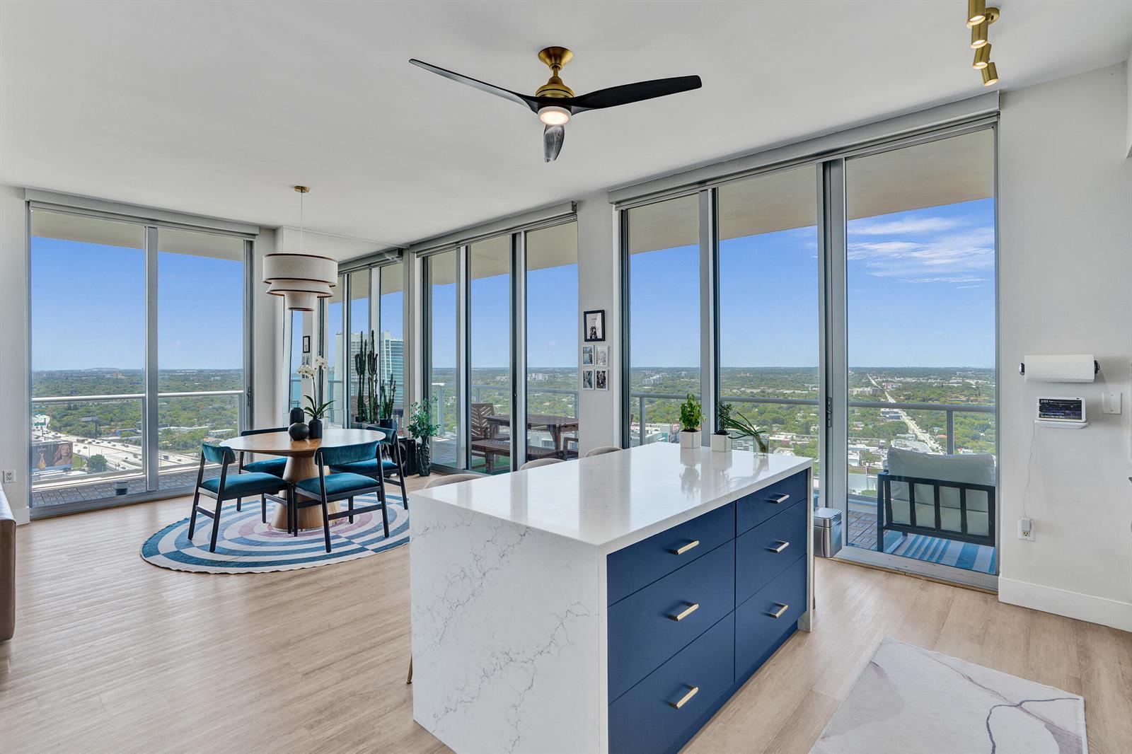 A modern apartment features a kitchen island, dining area, and floor-to-ceiling windows with city views — 3470 E Coast Avenue # H2704, Miami FL 33137, MIAMI, FL