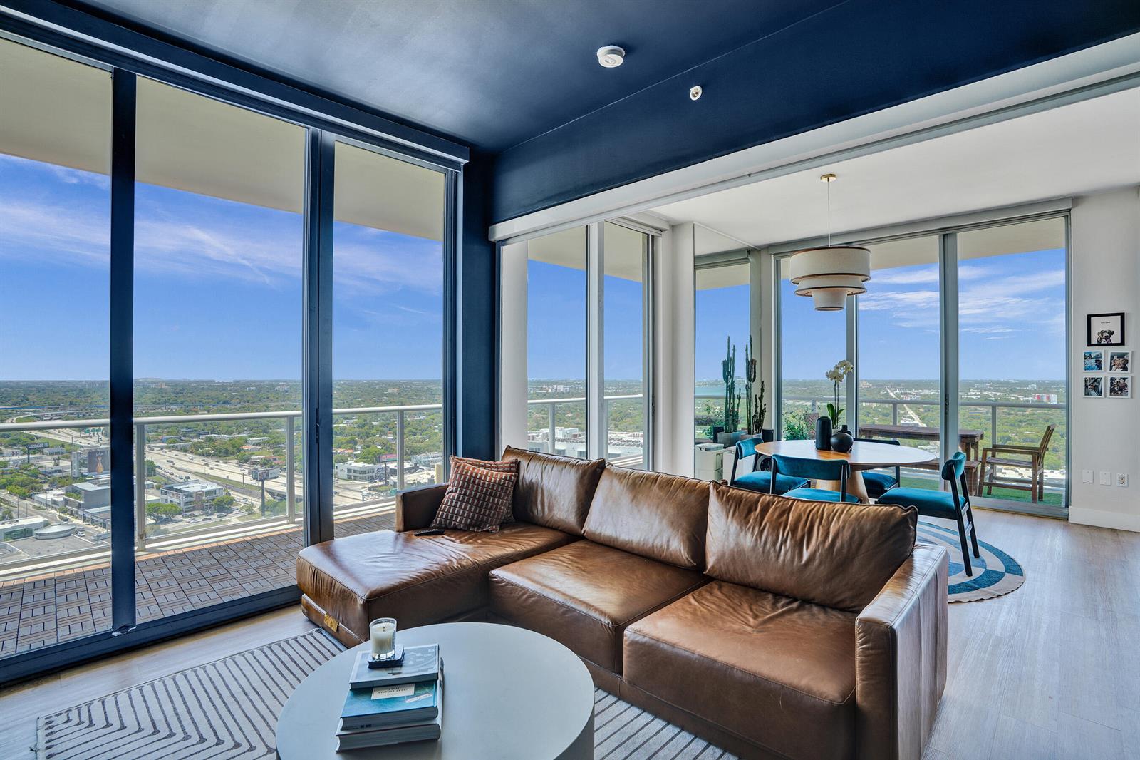 A modern living room with a leather sectional, round coffee table, and floor-to-ceiling city views — 3470 E Coast Avenue # H2704, Miami FL 33137, MIAMI, FL