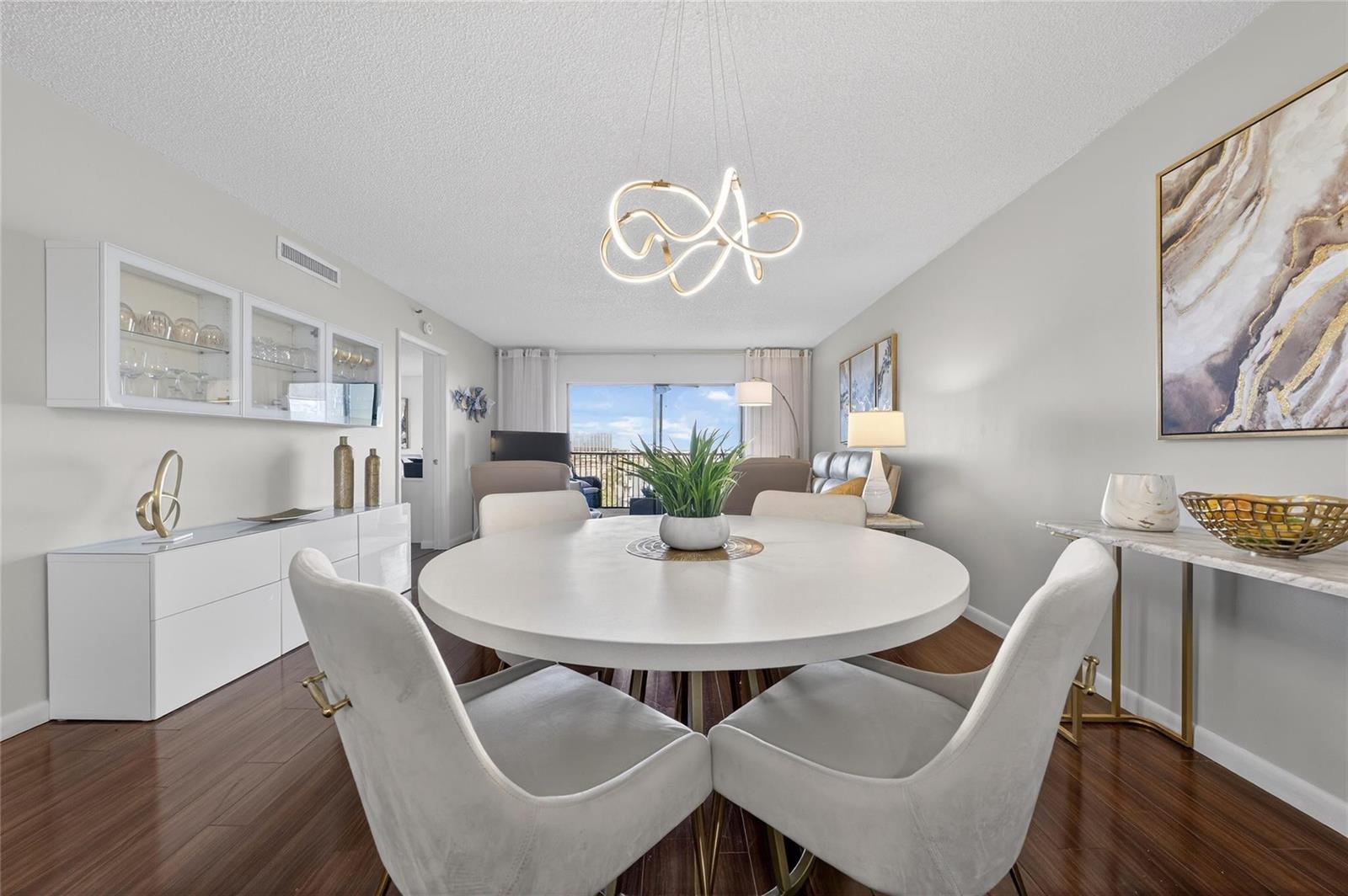 A dining area features a round white table, four upholstered chairs, and a modern light fixture — 2215 Cypress Island Drive # 701, Pompano Beach FL 33069, POMPANO BEACH, FL