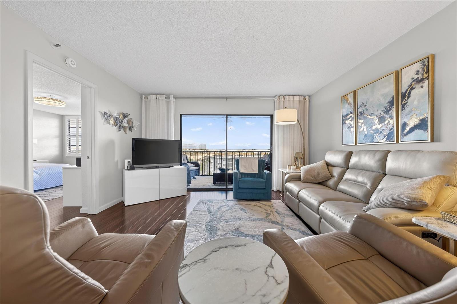 A living room features a leather sofa, two armchairs, a television, and a balcony view — 2215 Cypress Island Drive # 701, Pompano Beach FL 33069, POMPANO BEACH, FL