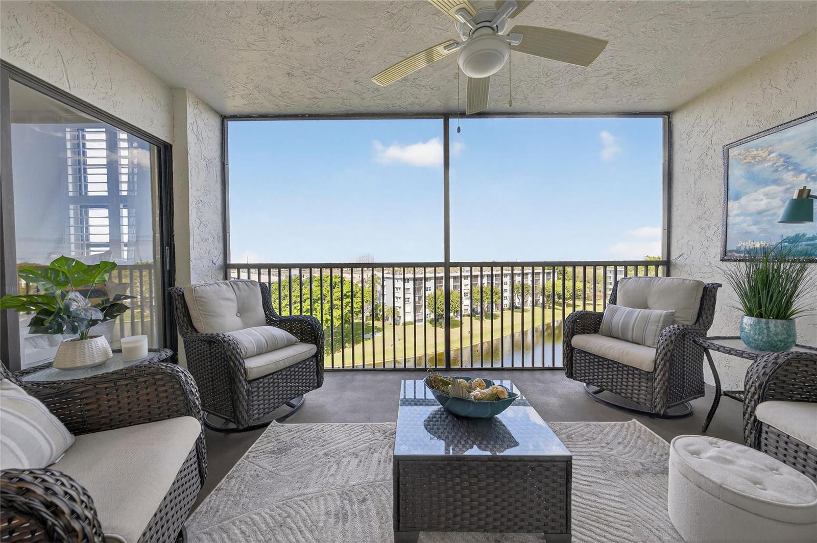 A screened-in balcony features wicker furniture, a ceiling fan, and a view of a pond — 2215 Cypress Island Drive # 701, Pompano Beach FL 33069, POMPANO BEACH, FL