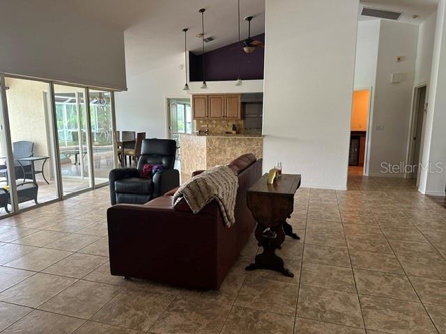A living room with tile floors, a brown sofa, a recliner, and an open kitchen — 4 PINEHURST PLACE, ROTONDA WEST, FL