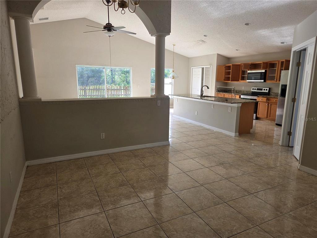 A kitchen with wood cabinets and a tile floor opens to a dining area — 725 ROBIN COURT, KISSIMMEE, FL