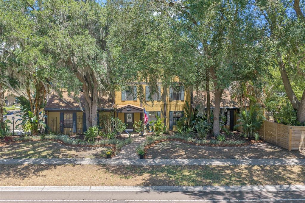 A two-story yellow house with dark shutters is surrounded by large, moss-draped oak trees — 314 BLOOMINGFIELD DRIVE, BRANDON, FL
