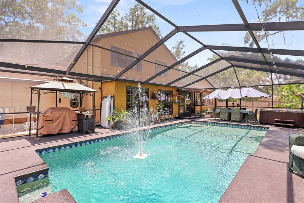 A screened-in pool area features a central fountain, a covered grill, and outdoor dining furniture — 314 BLOOMINGFIELD DRIVE, BRANDON, FL