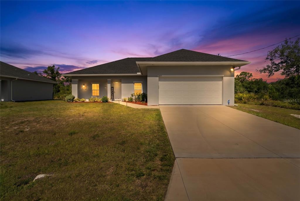 A single-story house with a two-car garage and a concrete driveway at sunset — 3271 JERSEY STREET, PORT CHARLOTTE, FL