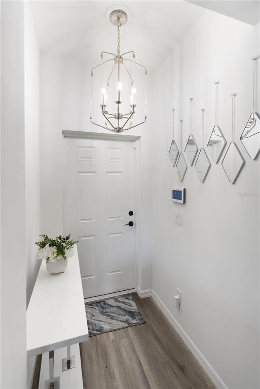 A bright entryway features a white console table, a modern chandelier, and wall-mounted diamond mirrors — 3271 JERSEY STREET, PORT CHARLOTTE, FL