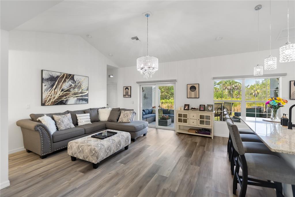 A living room with gray sectional seating, a patterned ottoman, and wood-look flooring — 3271 JERSEY STREET, PORT CHARLOTTE, FL